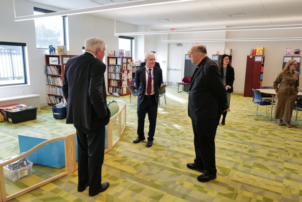 Cardinal McElroy, Bill Conway, and Jim Malloy standing talking in the Conway Education Center library.